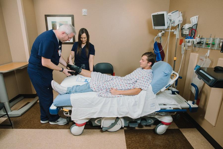 Doctor and nurse examining male patient's foot in brace